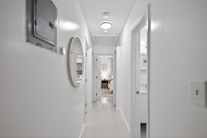 Un pasillo con paredes blancas, una lámpara en el techo y una puerta que da a una habitación.