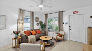 A modern living room with a ceiling fan, a sofa, a round coffee table, and a chair. - Family Getaway • Huge Yard • Near Beach• 3BR (Hallandale Beach)