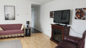 Una sala de estar con sofá, televisión, chimenea y un cuadro en la pared.