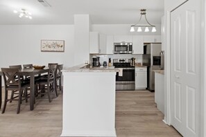 Eine moderne Küche mit weißen Schränken, einer zentralen Kochinsel und einem Essbereich mit Holzkästen.