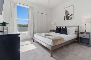 Ein Schlafzimmer mit Bett, Nachttischen, Schreibtisch und einem Fenster mit Vorhängen.
