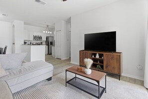 Ein modernes Wohnzimmer mit einer Couch, einem Couchtisch, einem Fernseher und einem Holzschrank.