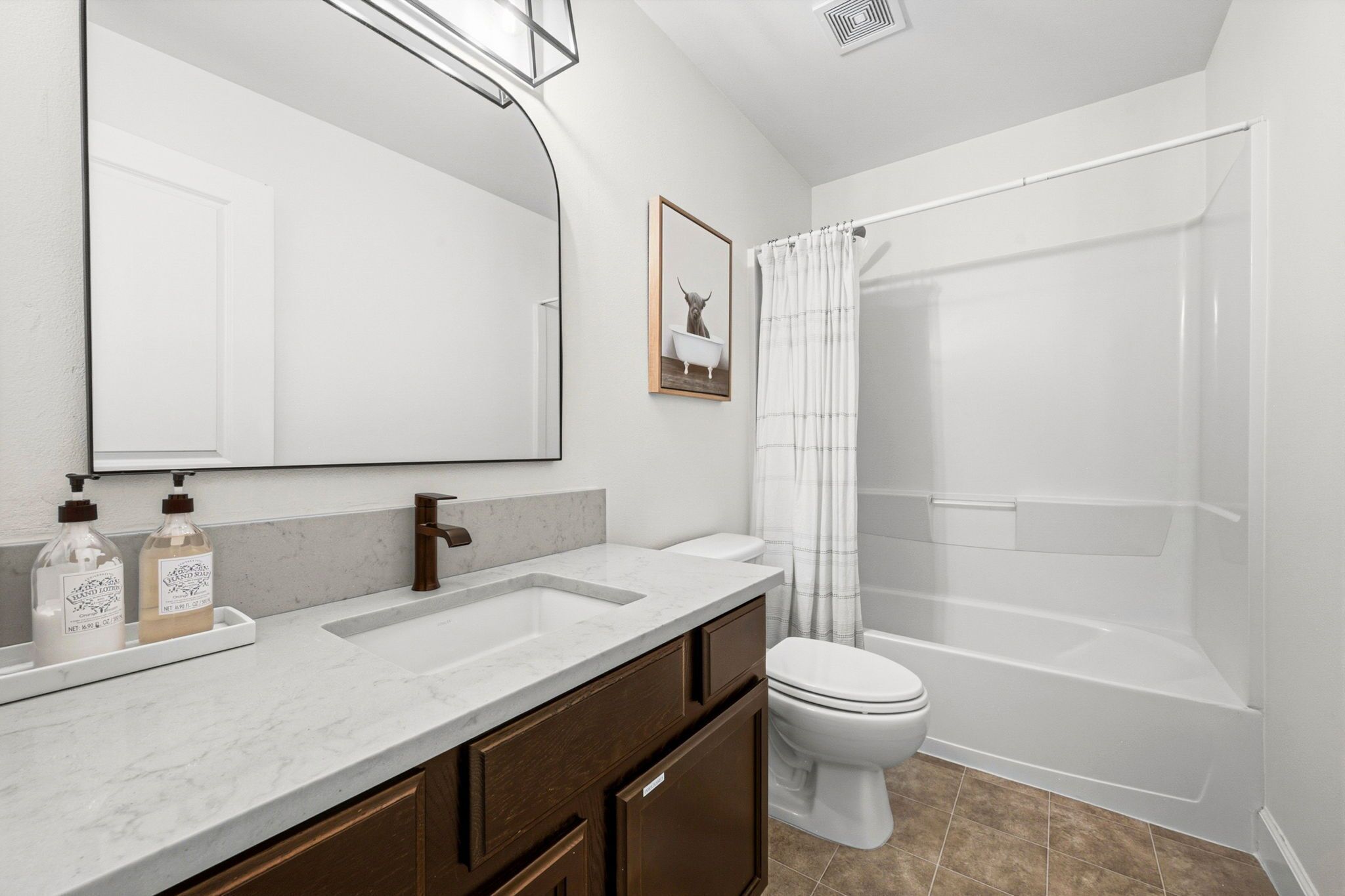 A bathroom with a large mirror, a sink, a toilet, and a shower.