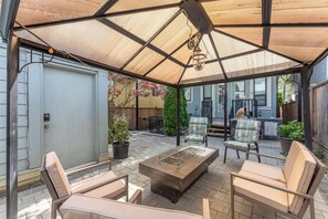 Un patio techado con una mesa, sillas, una puerta y plantas en macetas.