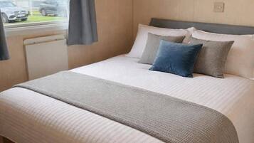 Quarto com cama, janela com cortinas, armário de madeira sobre a cama e vista para o exterior.