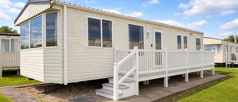 A mobile home with a covered porch and a small set of stairs leading to the entrance.