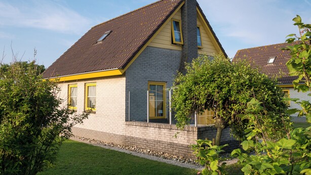 Et toetagers hus med skråtag, skorsten og et lille vindue.