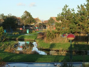 A park with a pond, playground equipment, and a red lamp post. - A lovely vacation home where the whole family can relax and unwind on the coast (Julianadorp)