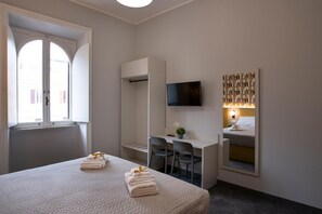 A hotel room with a bed, a desk, a chair, a TV, and a window. - Standard Room for 1 to 4 people in Piazza Bologna (Roma)