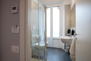 Ein Badezimmer mit Duschkabine, Toilette, Waschbecken und Handtuchhalter.