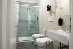 Ein modernes Badezimmer mit einer Duschkabine aus Glas, einem weißen Waschbecken und einer Toilette.