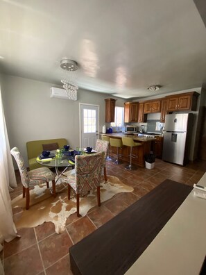 A kitchen with wooden cabinets, a refrigerator, a stove, and a dining area with chairs and a table. - 2-bedroom House Getaway in Puerto Peñasco w/ AC comfort; 7 mins from the beach (Puerto Peñasco)