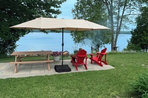 Ein Picknick mit Tisch, Stühlen und Sonnenschirm am Seeufer.