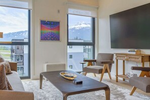 Ein modernes Wohnzimmer mit großem Fenster, Flachbildfernseher und einer gemütlichen Sitzecke.