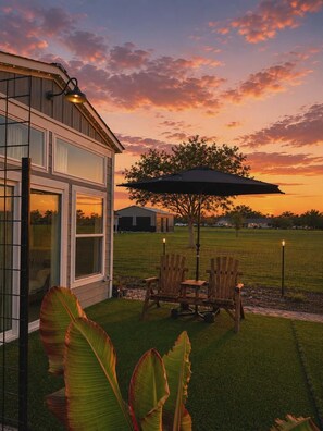 Une maison moderne dotée d’un patio, de mobilier d’extérieur et d’un grand parasol.