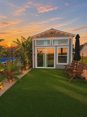 Une maison moderne dotée d’une grande porte vitrée, d’une piscine et d’une pelouse bien entretenue.