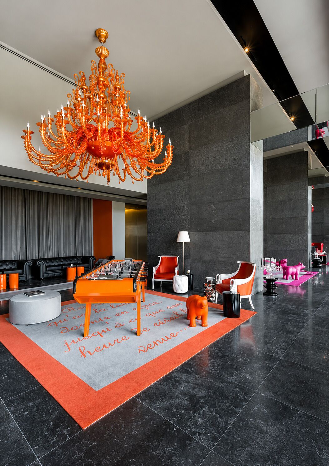 A lobby with a large chandelier, a foosball table, and modern seating.