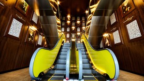 A modern interior with two escalators, wooden paneling, and decorative wall panels. - Yoo Panama Luxury Ocean View Apartment (Panamá)