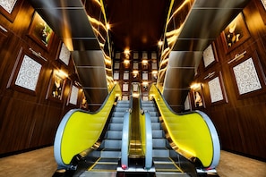 A modern interior with two escalators, wooden paneling, and decorative wall panels. - Yoo Panama Luxury Ocean View Apartment (Panamá)