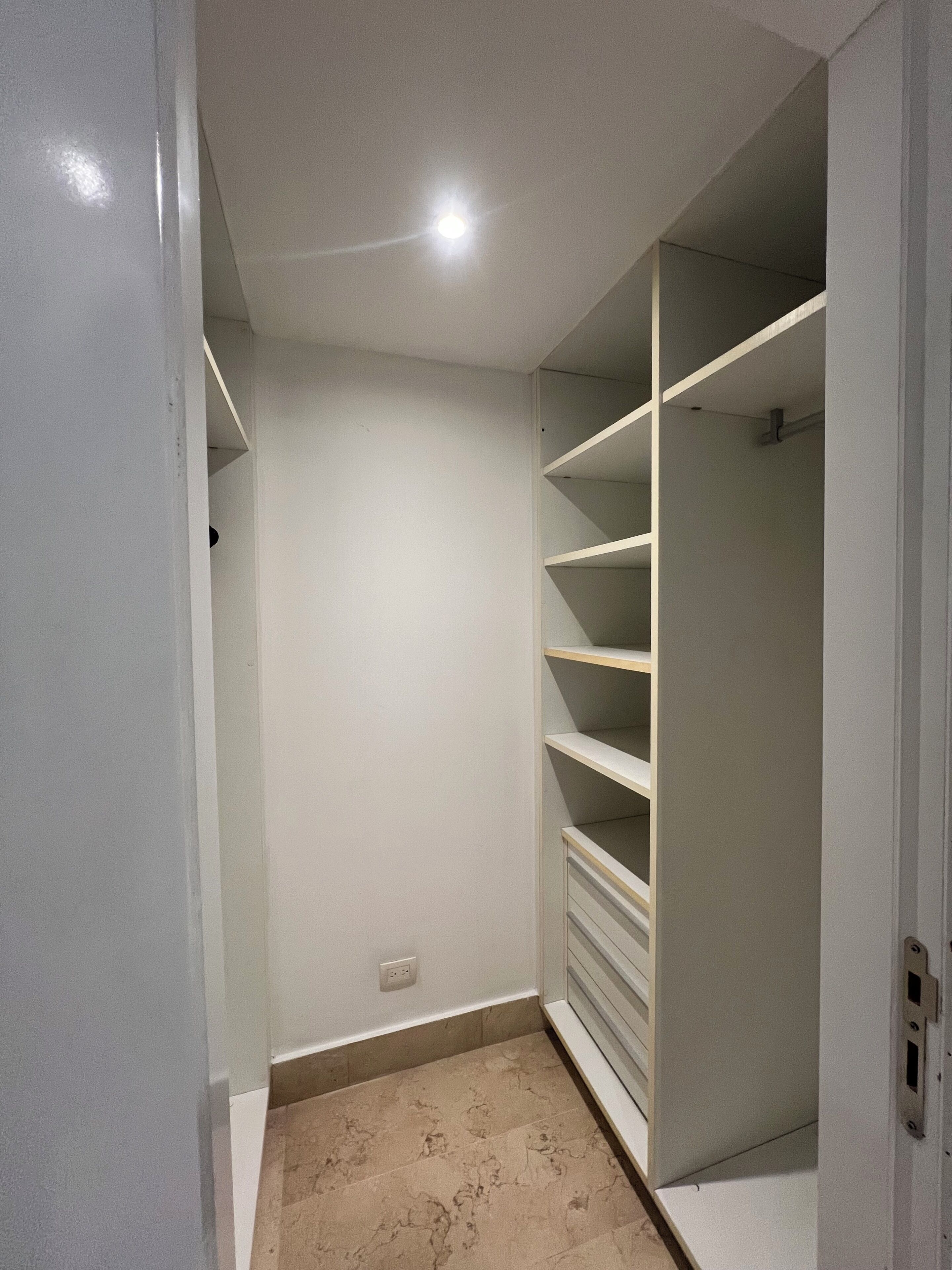 Armadio a muro con pareti bianche, pavimento piastrellato e una luce a soffitto.
