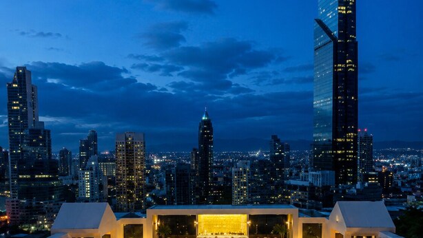 A rooftop pool with lounge chairs and a bar, overlooking a city skyline at dusk. - Yoo Panama Luxury Ocean View Apartment (Panamá)