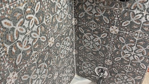 Ett badrum med väggar beklädda med mosaik, ett vitt badkar och en dusch.