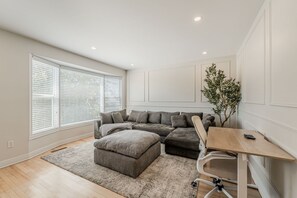 Un salon moderne avec un canapé d’angle, une petite table en bois et une plante en pot.