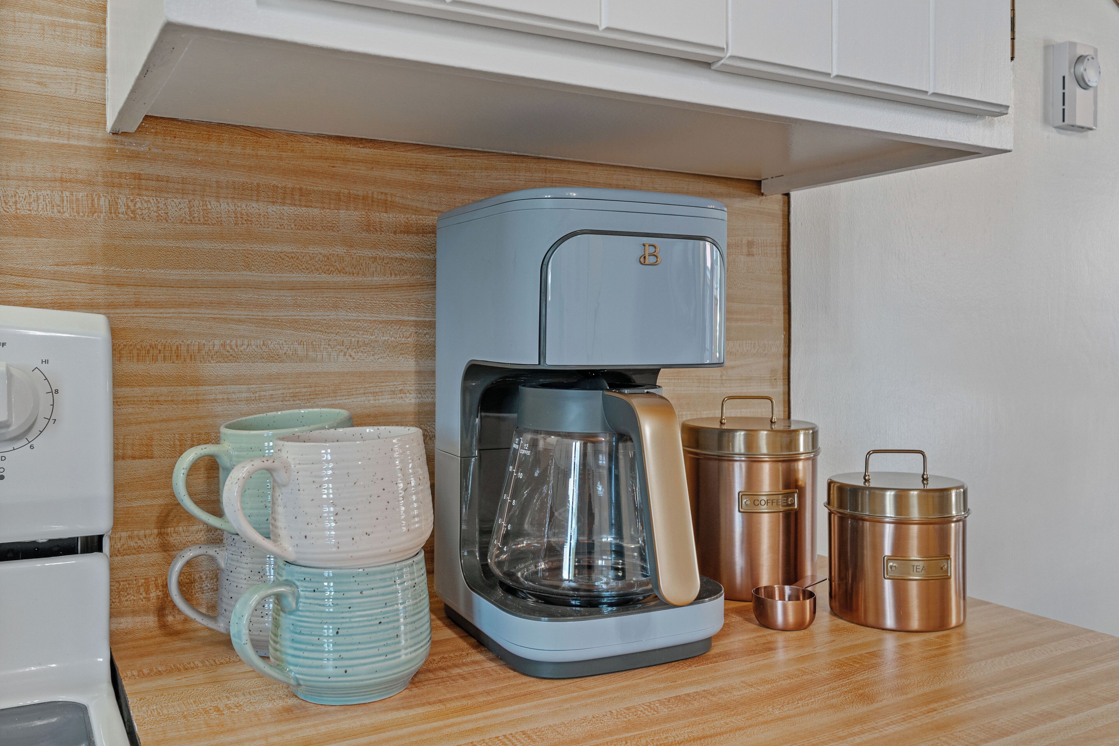 Une cuisine équipée d’une machine à café, de deux tasses, d’une bouilloire et de deux récipients en acier inoxydable.