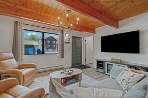 Una sala de estar moderna con un sofá, una mesa de centro, un televisor y una chimenea.