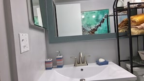 Ein Badezimmer mit Waschbecken, Spiegel, Handtuchhalter und Steckdose.