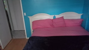 Ein Zimmer mit einem Bett, einer Tür und einer blauen Wand.