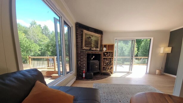 A living room with a fireplace, a sofa, a coffee table, and a view of the outdoors.