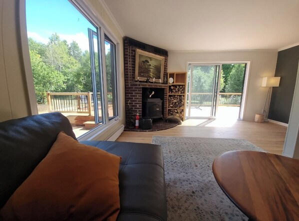 A living room with a fireplace, a sofa, a coffee table, and a view of the outdoors.