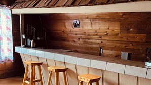 Um interior em madeira com área de bar, banquetes e um tapete estampado.