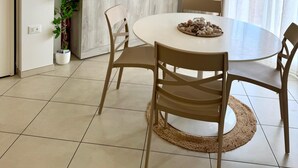 A modern kitchen with a white countertop, a flat-screen TV mounted above it, and a dining area with a round table and chairs. - Tourist Location Giancola between Seas and Mountains (Bellante Stazione)
