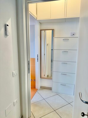 A hallway with a white door, a mirror, and a white cabinet with drawers. - Tourist Location Giancola between Seas and Mountains (Bellante Stazione)