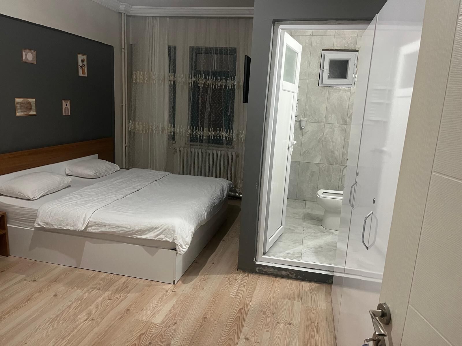 A bedroom with a bed, a shower area, and a window with curtains.