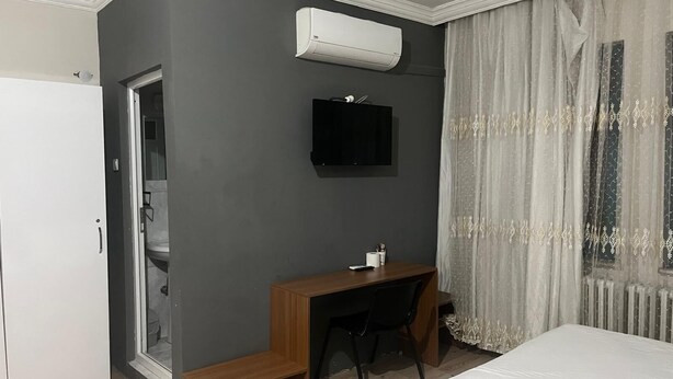 Un dormitorio con cama, escritorio, silla, inodoro y aire acondicionado.
