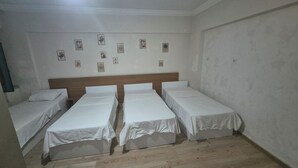 Una habitación con tres camas individuales, un cabecero de madera y una pared decorada con cuadros.
