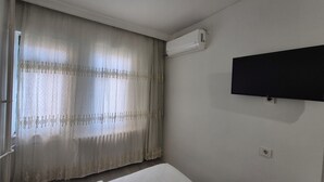 Una habitación con cama, televisión montada en la pared y aire acondicionado.