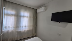 Una habitación con cama, televisión montada en la pared y aire acondicionado.