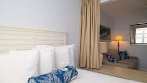 Ett hotellrum med en säng, en soffa, en lampa och en spegel.