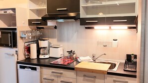 A modern kitchen with a dishwasher, coffee maker, toaster, and a cutting board. - Apartmenthaus Am Kornfeld  (Lünen)