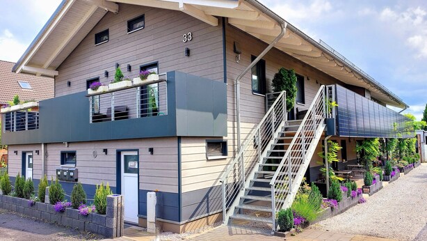 A modern two-story building with a visible staircase, a small balcony with plants, and a number '33' on the facade. - Apartmenthaus Am Kornfeld  (Lünen)