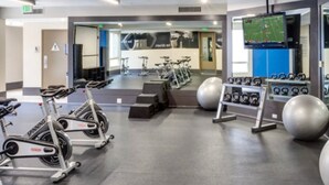 Une salle de sport équipée de vélos d’appartement, de kettlebells et de ballons d’exercice.