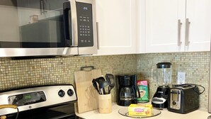 Une cuisine équipée d’un four à micro-ondes, d’une cuisinière, d’un four et de divers appareils, comme un mixeur et un grille-pain.