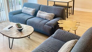 Un salon moderne avec un canapé gris, une petite table basse ronde et une table à manger.