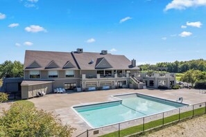 Ein großes Gebäude mit Schwimmbad, Außenbereich mit Sitzgelegenheiten und einer überdachten Terrasse.