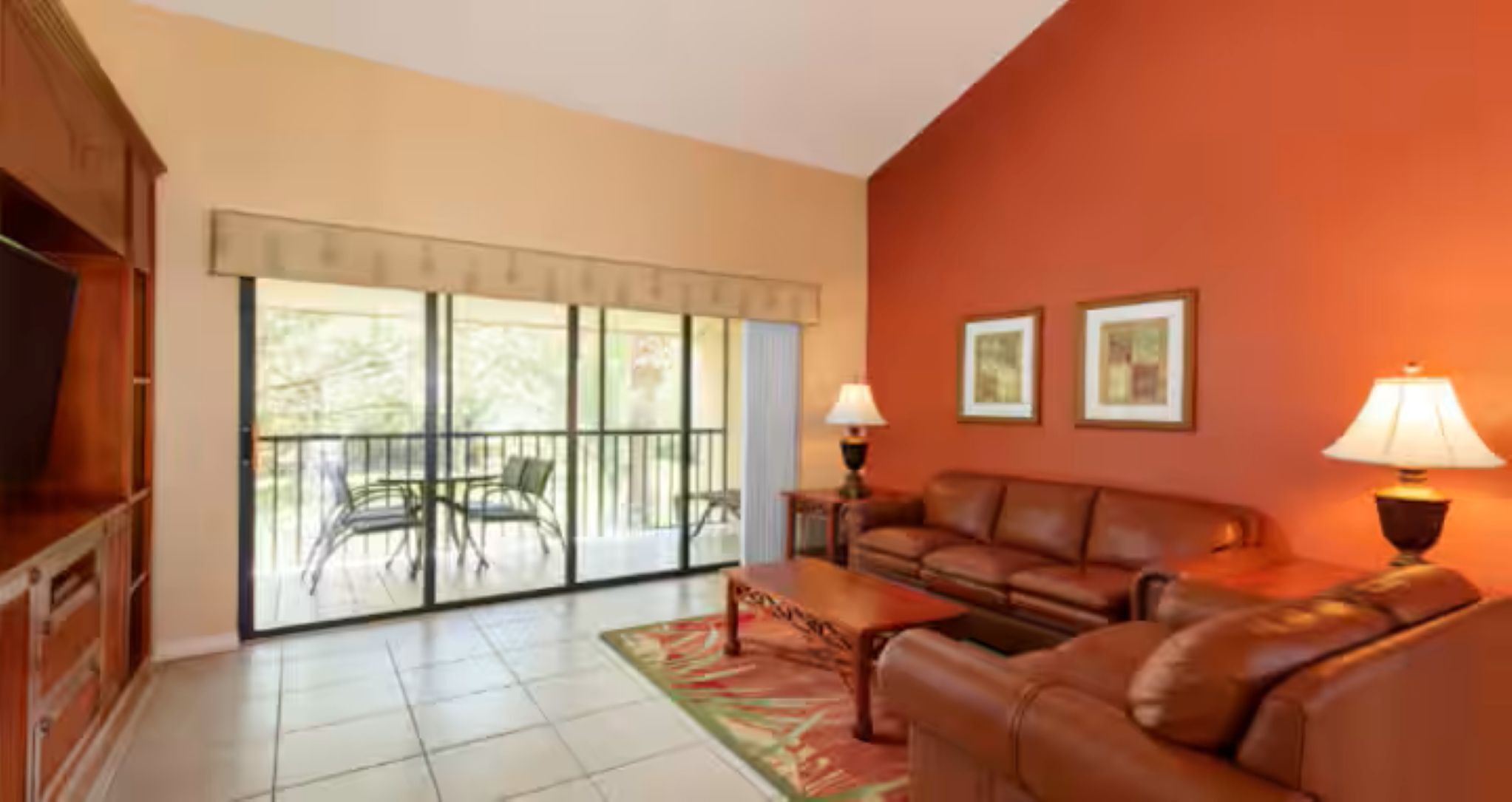 A living room with a sofa, two lamps, a coffee table, and a balcony with chairs.