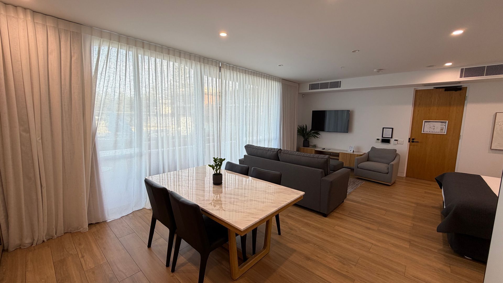 A modern living room with a dining table, sofa, and TV.